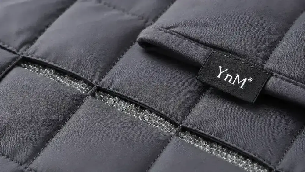 Close-up of weighted blanket glass beads texture, stitched grid pattern on grey fabric