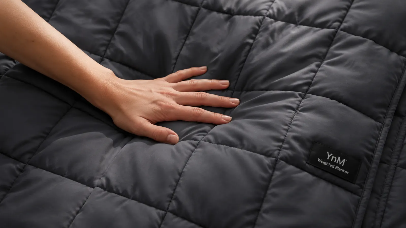 Hand pressing down gently on the surface of a weighted blanket to show the firmness and glass bead fill