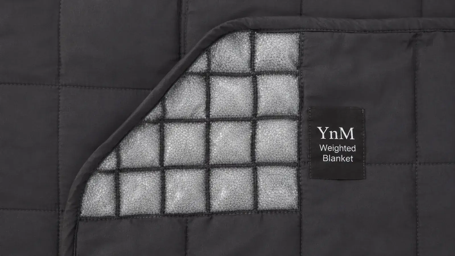 Person pulling a weighted blanket up to their shoulders while lying in bed at night